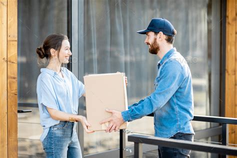 Delivery Man Bringing Goods Home For A Woman Client Stock Photo By