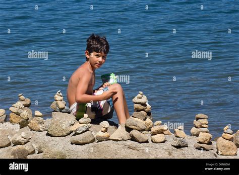 Kleiner Junge Am Strand Mit Haufen Von Gestapelten Steinen Um Ihn Herum