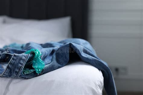 Unrolled Condom And Jeans On Bed In Bedroom Safe Sex Stock Image