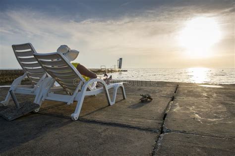 A Woman In A Hat Is Lying On A Deckchair On The Beach At Dusk Stock Image Image Of Summer