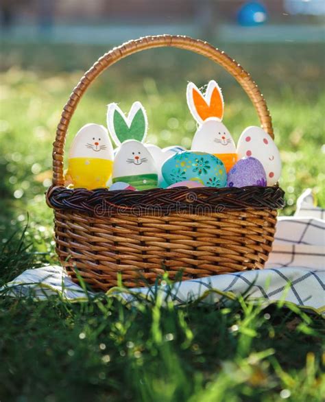 Hand Painted Easter Eggs In Rattan Basket On Green Grass With White