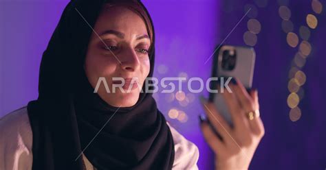 سيدة عربية تقوم بجلسة تصوير في المنزل ، إجراء مكالمة فيديو بإستخدام الهاتف المحمول، العمل عن بعد