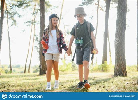 Boy And Girl Go Hiking With Backpacks On Forest Road Bright Sunny Day