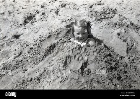 1960s Historical Holiday Fun At The Seaside A Little Girl Buried Or