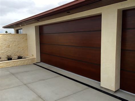 A House With Two Brown Garage Doors In Front Of It And A Planter On The