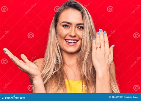 Young Beautiful Blonde Woman Showing Engagement Ring Over Isolated Red Background Celebrating