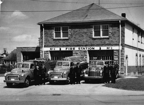 An Old Black And White Photo Of Fire Station With Several Trucks Parked