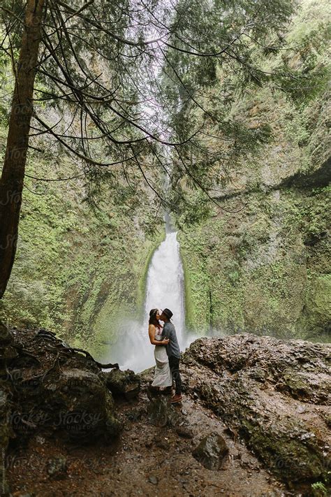 Beautiful Couple Kissing In Front Of Waterfall By Stocksy Contributor