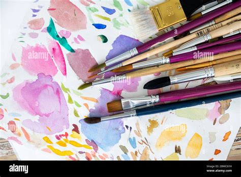 Multiple Painting Brushes Laying On Colorful Watercolor Background