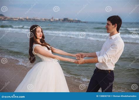 happy loving couple newlyweds hold each others hands on ocean beach beautiful bride and groom