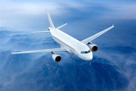 White Passenger Plane Fly Above The Mountain Landscape Front View Of