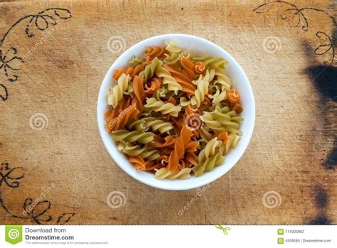 Multicolor Spiral Macaroni Pasta In A White Cup On A Wooden Cutting