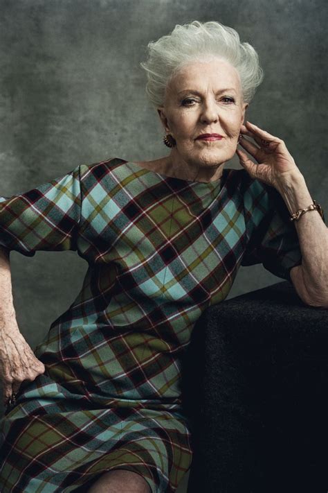 An Older Woman Sitting In A Chair With Her Hand On Her Chin And Looking At The Camera