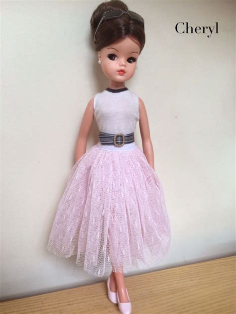 The Doll Is Wearing A Pink Dress And White Shoes With A Black Belt