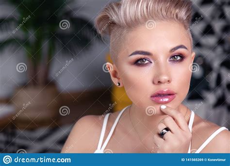 closeup portrait blonde model with bright make up and short hair with shaved temples in modern