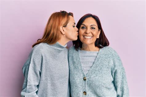 Latin Mother And Daughter Wearing Casual Clothes Looking At The Camera Blowing A Kiss On Air