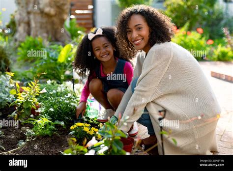 Happy African American Mother And Daughter Planting Flowers Stock Photo