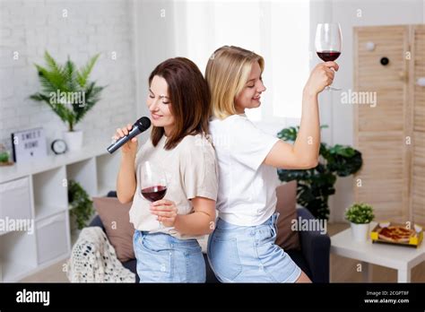 Home Party Portrait Of Two Beautiful Girls Having Fun Together Drinking Wine Dancing And