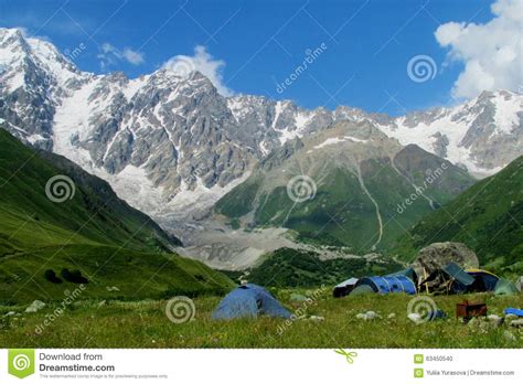 High Snow Mountain Range Above Camping Tents In Green