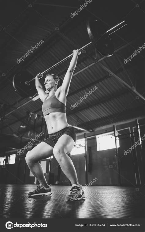 modelo fitness femenino haciendo ejercicios levantamiento pesas cross fit gimnasio fotografía