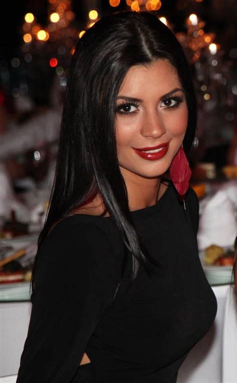 a woman with long black hair and red lipstick posing for the camera at an event