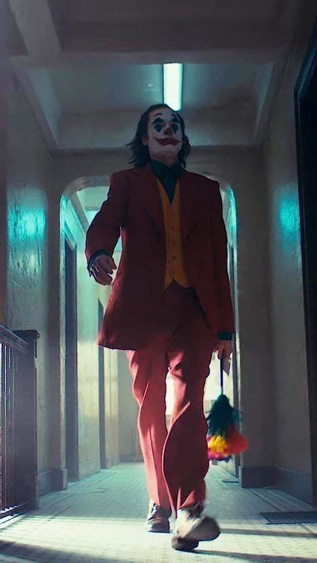 A Man In A Red Suit And Clown Mask Walking Down A Hallway With An Umbrella