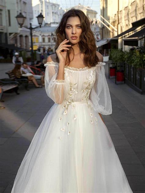 A Line Wedding Gown With An Off The Shoulder Neckline Bishop Sleeves And Floral Appliqué