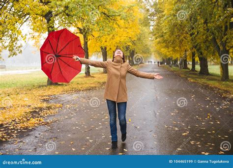 Gelukkige Vrouw Die Met Rode Paraplu Bij De Regen In Mooi De Herfstpark Lopen Stock Afbeelding