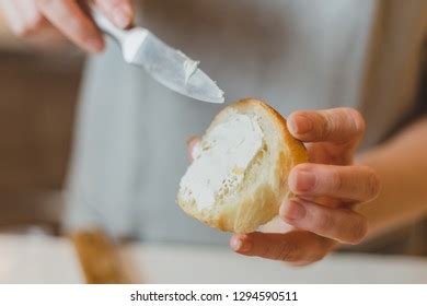 Woman Spreading Cream Cheese On Baguette Stock Photo