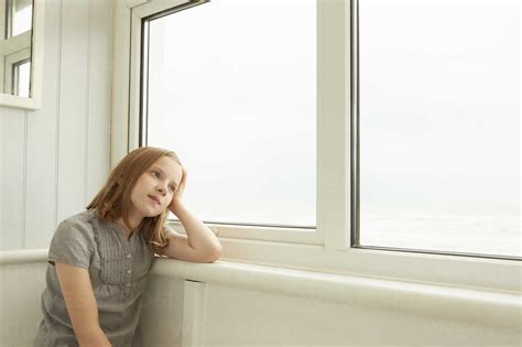 Portrait Of Girl Gazing Out Of Holiday Apartment Window Stock Photo