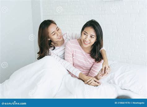 two pretty best friends forever girlfriend talk hug and laugh together on bed at cozy home