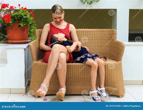 Mother And Young Daughter Are Sitting In A Rattan Chair Of A Mediterranean Hotel Stock Image