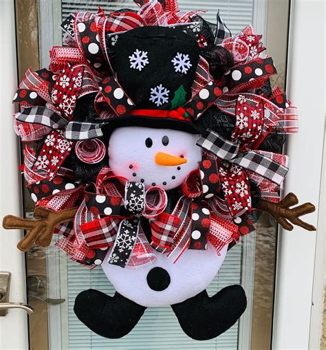 A Snowman Wreath Is Hanging On The Front Door With Red Black And White