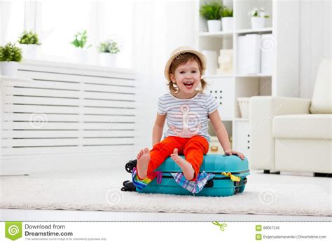 Happy Child Girl Packs Clothes Into Suitcase For Travel Vacation Stock