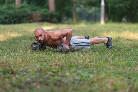 Young Man Exercising Push Ups With Dumbbells Outdoors Stock Photo