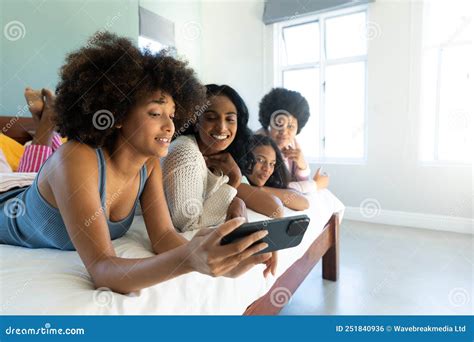 Biracial Woman With Afro Hair Taking Selfie Over Cellphone With Friends Lying Side By Side On