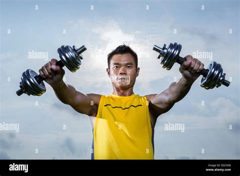 Athletic Young Chinese Man Exercising Outdoors With Dumbbells Muscular