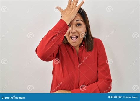 hispanic mature woman standing over white background surprised with hand on head for mistake