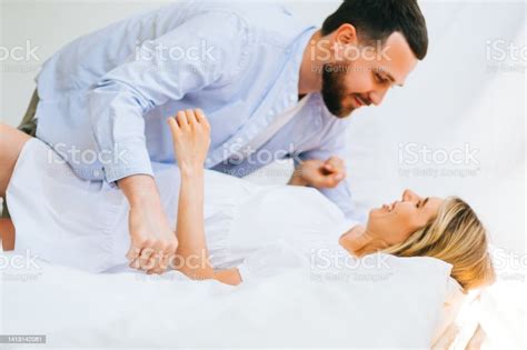 Happy Young Couple Lying On A Bed Husband Kissing Wife And Hug Stock