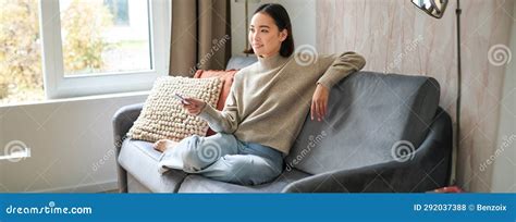 Portrait Of Modern Woman Sitting At Home With Remote Relaxing On