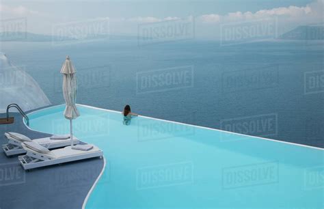 Caucasian Woman In Infinity Pool Admiring Scenic View Of Ocean Stock