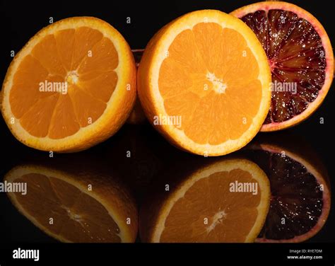 Red And Orange Juicy Oranges Fruits On A Black Background With Glass