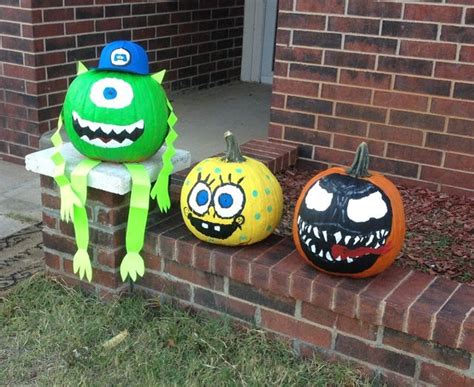Three Decorated Pumpkins Sitting On The Side Of A Brick Building