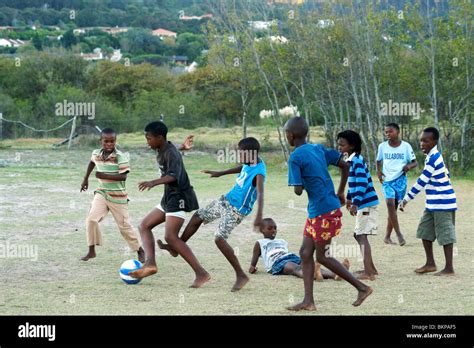 African Children Playing Soccer Barefoot In A Field In Hout Bay In Cape
