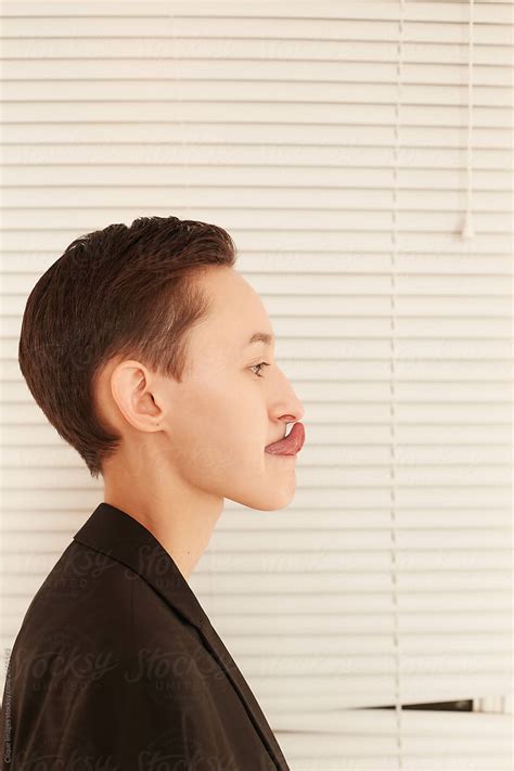 Gender Neutral Model Touching Nose With Tongue Near Window By Clique Images