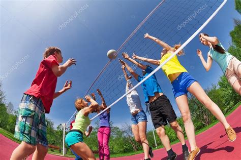 Adolescentes jugando voleibol en la cancha de juego fotografía de stock serrnovik