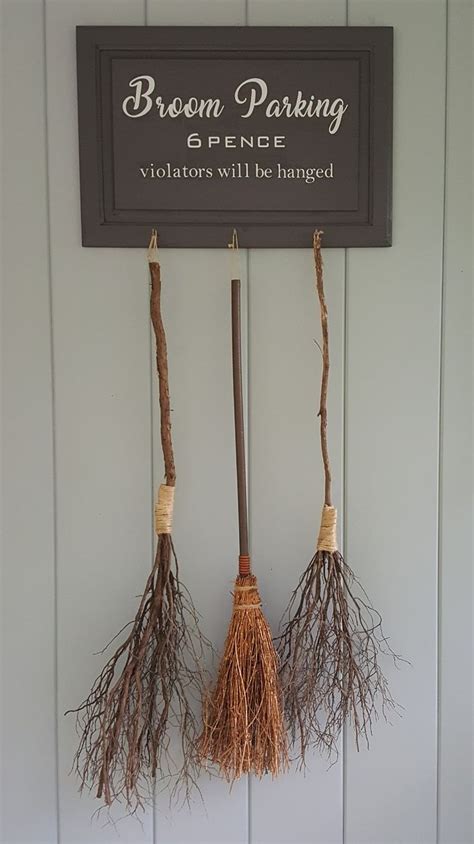 Three Brooms Hanging From The Side Of A Wall With A Sign Above Them