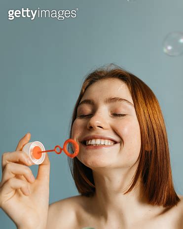 Model with naked shoulders smiling and blowing bubbles 이미지 게티이미지뱅크