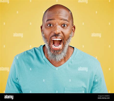 Mature African Man Looking Surprised Against A Yellow Studio Background
