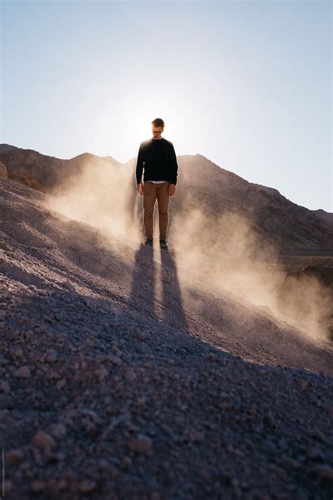 Young Man Standing Tall With Sunlight At His Back And Dust Flying